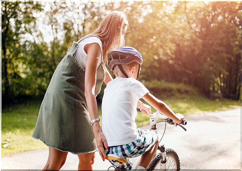 Mother helping her son to ride a bicycle.