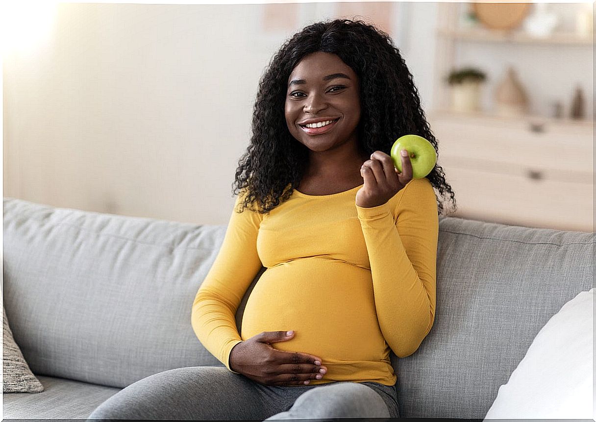 Pregnant woman eating apple during pregnancy, one of the easy to digest foods.