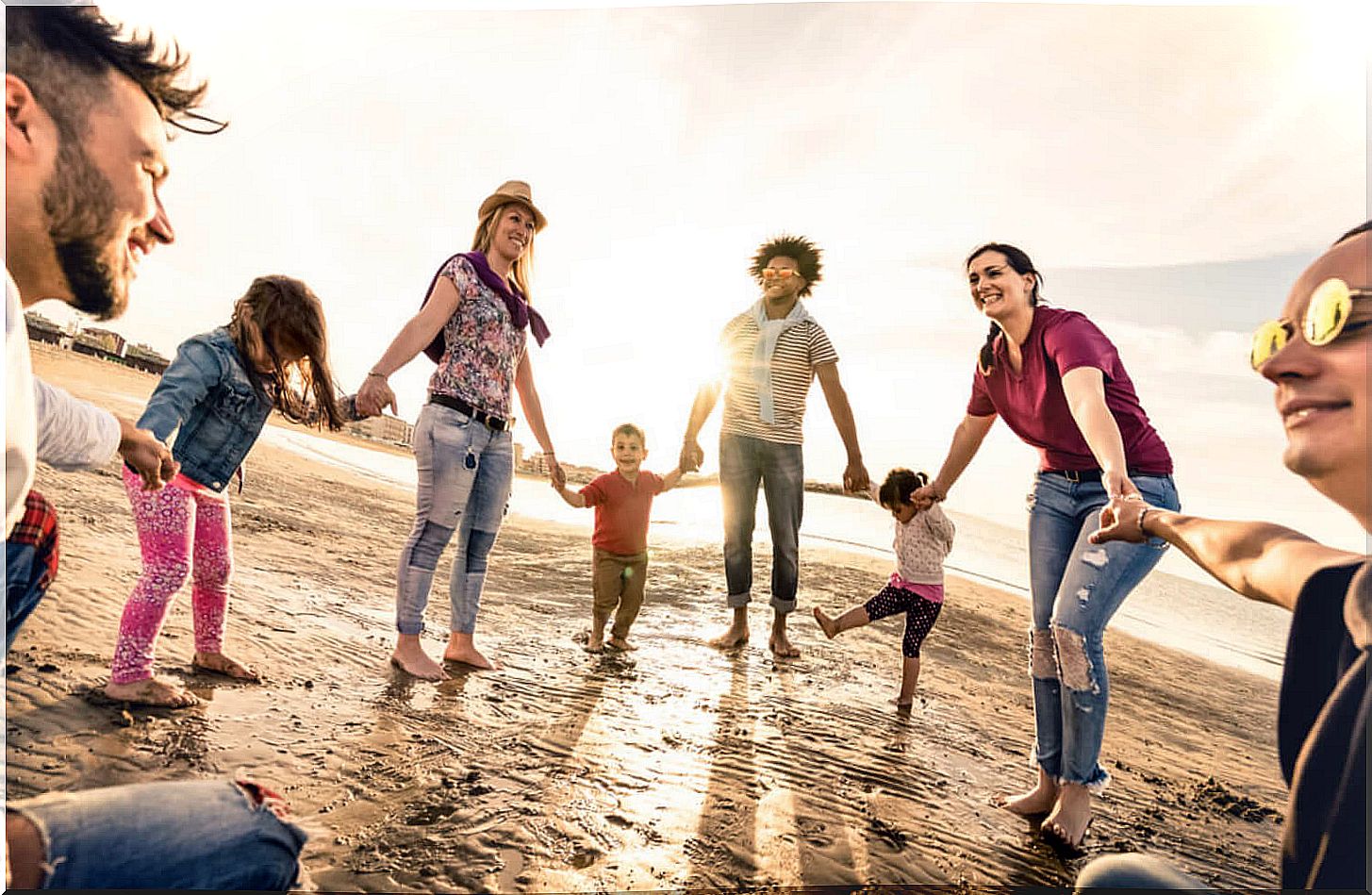 Parents and children shaking hands on the beach for an intercultural education.