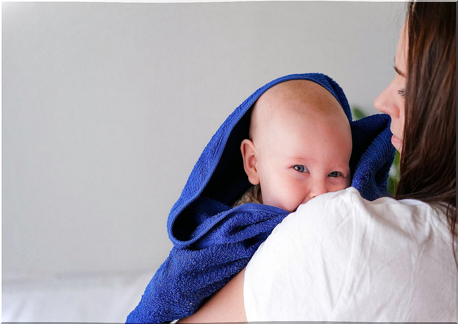 Mom wrapping her baby in a towel after bathing to take care of her skin.