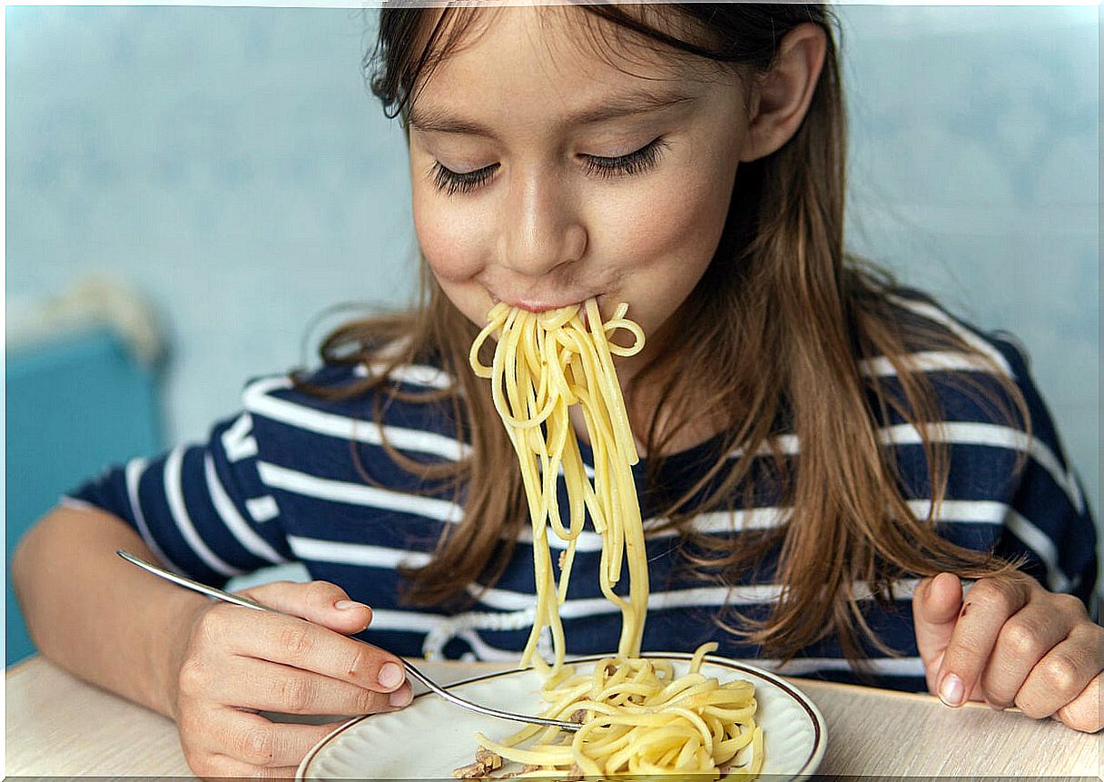 Girl eating a plate of pasta, one of the foods that seems healthy, but is not.