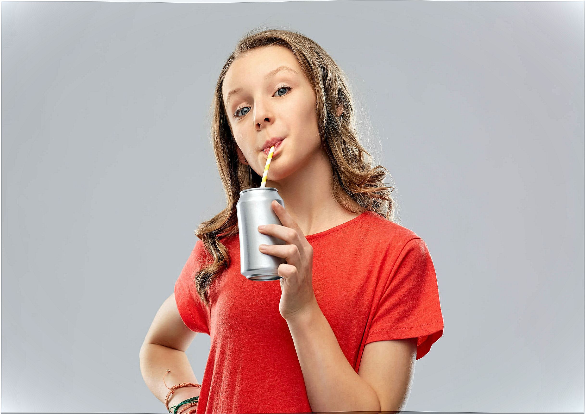 Teen girl drinking a soda with a lot of carbohydrates and sugar.