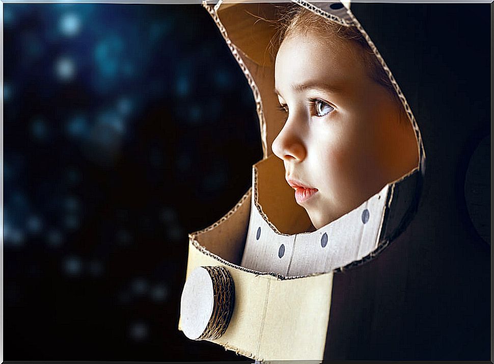 Little girl wearing a cardboard astronaut helmet after reading some of the children's books for little astronauts.