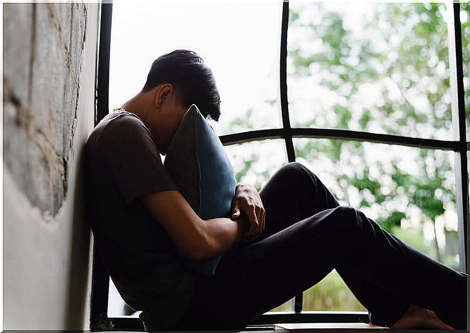 Teenager sitting at the window exhausted and stressed.