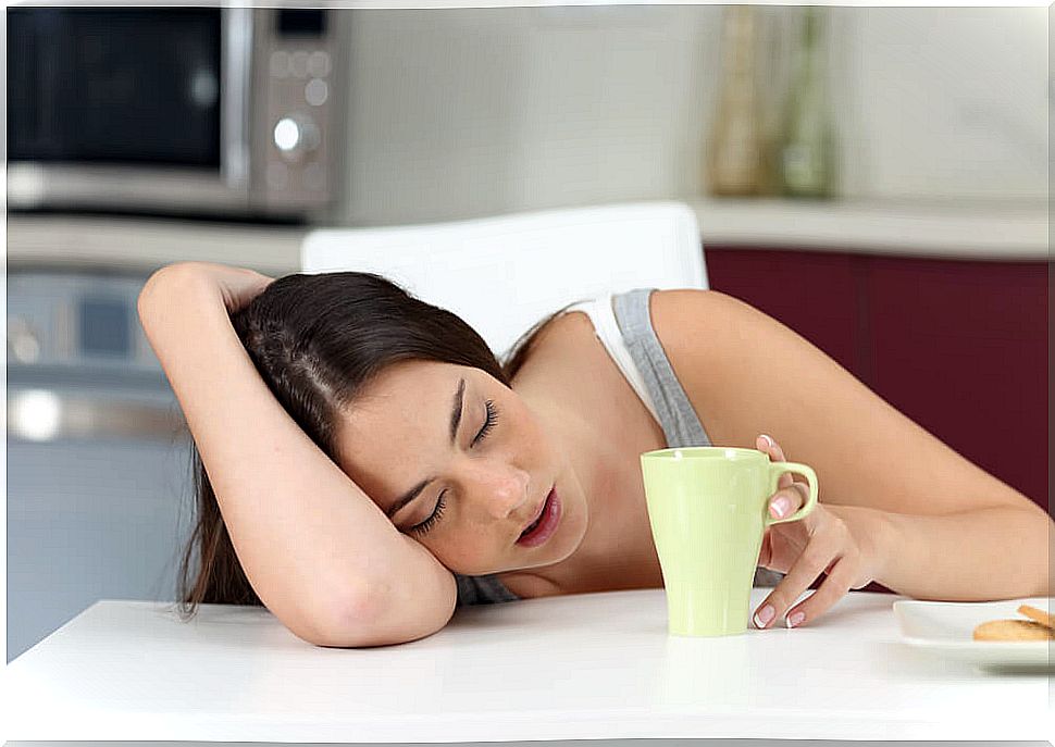 Teen half asleep while having morning coffee.