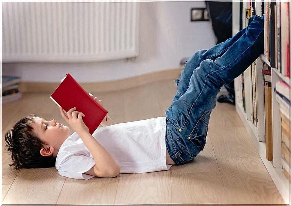 Boy reading a book by Isadora Moon lying on the floor.