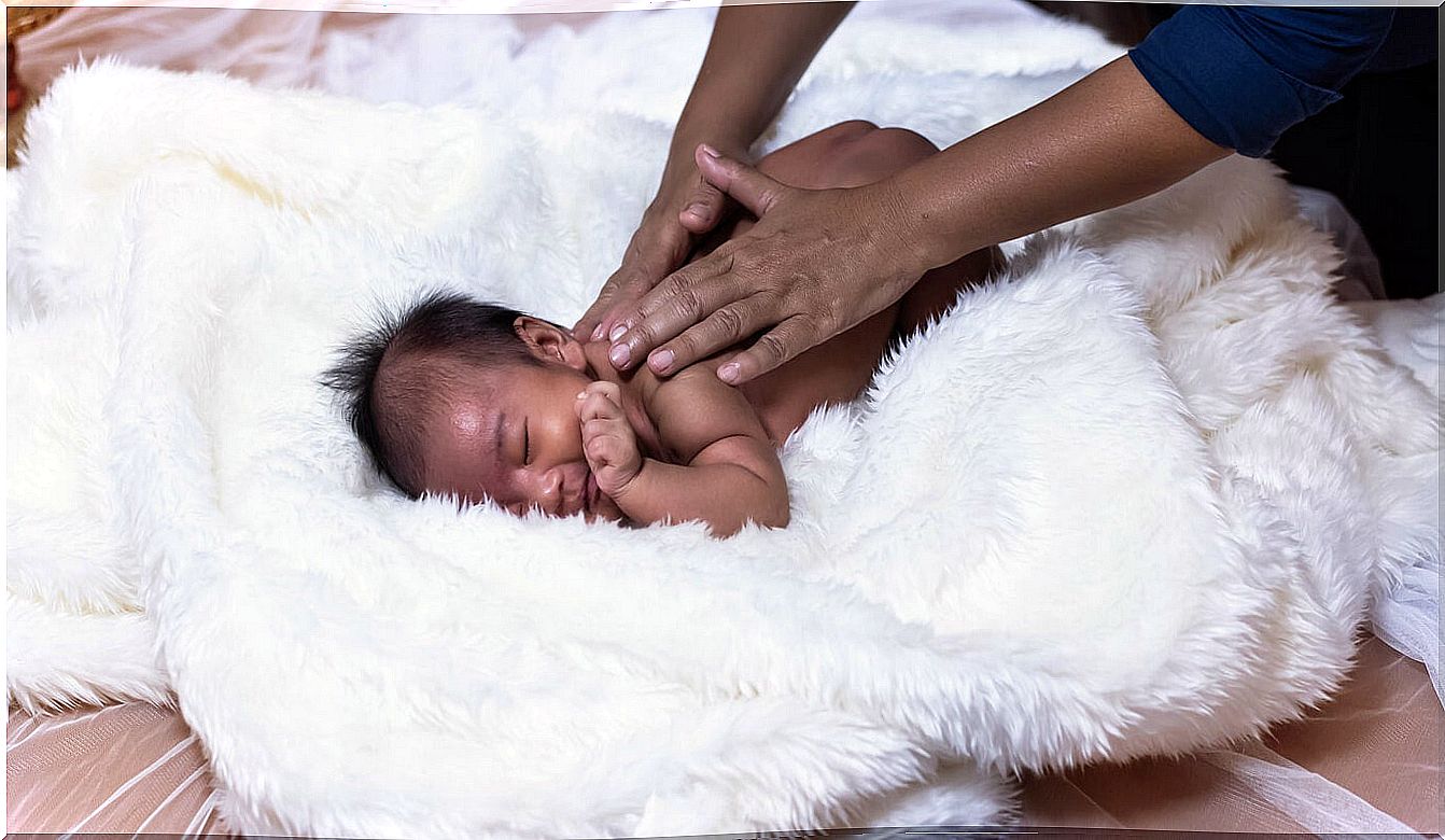 Mother giving a massage to her newborn baby to benefit from the virtues of massage.