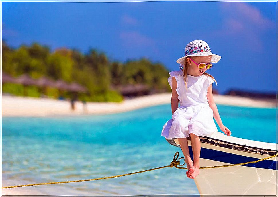 Girl sitting in a boat on the shore of the beach about to go sailing.