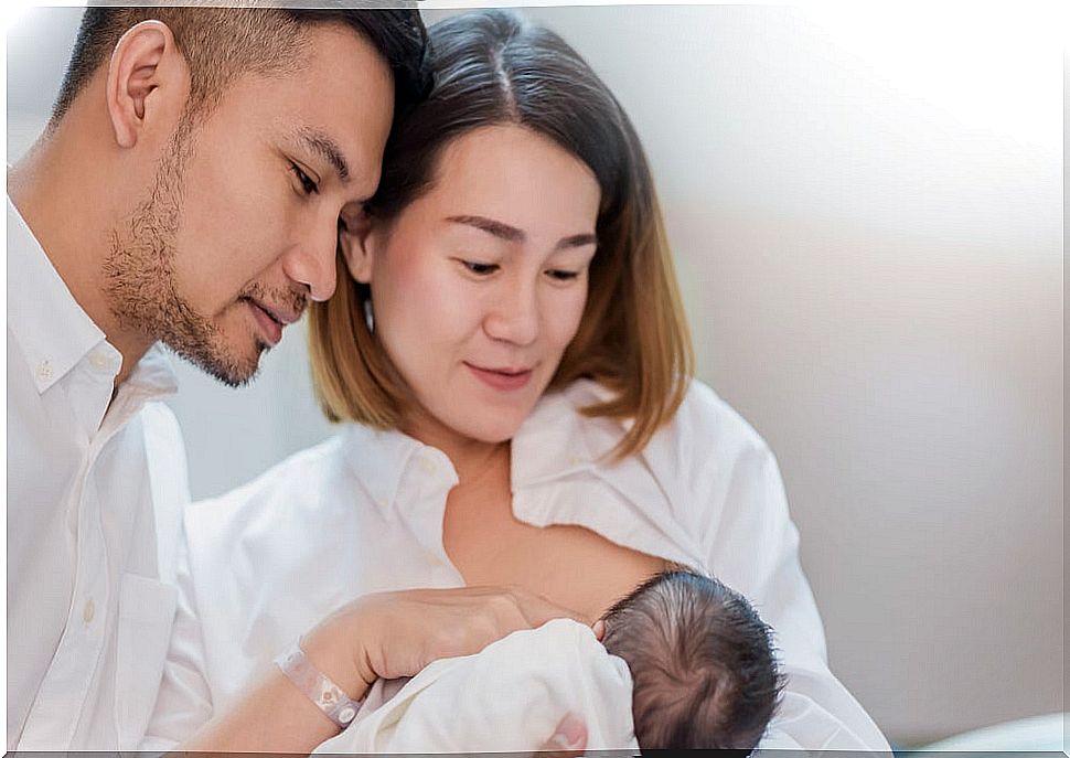 Father supporting his wife while breastfeeding her baby.