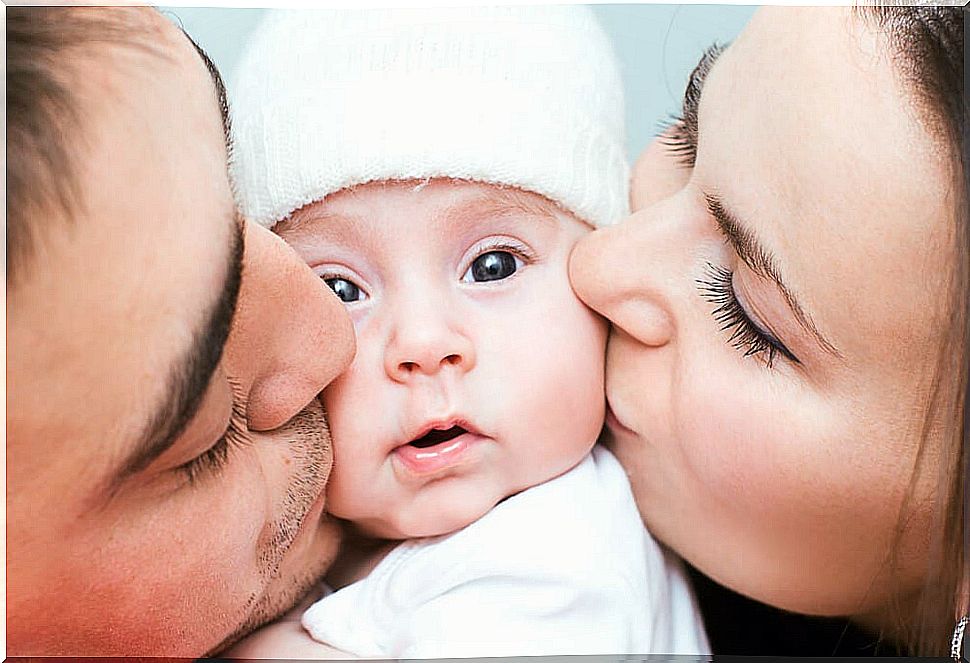 Parents giving their baby a kiss.