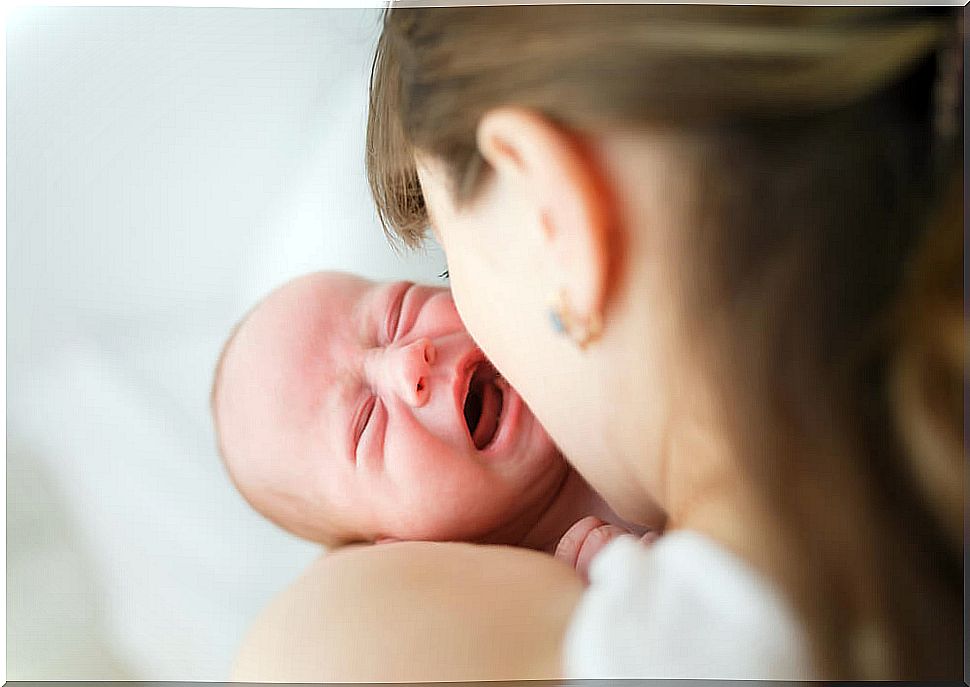 Crying child in his mother's arms after suffering shaken child syndrome.