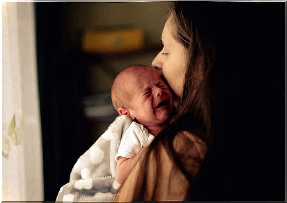 Baby crying while his mother hugs him to avoid shaken baby syndrome.