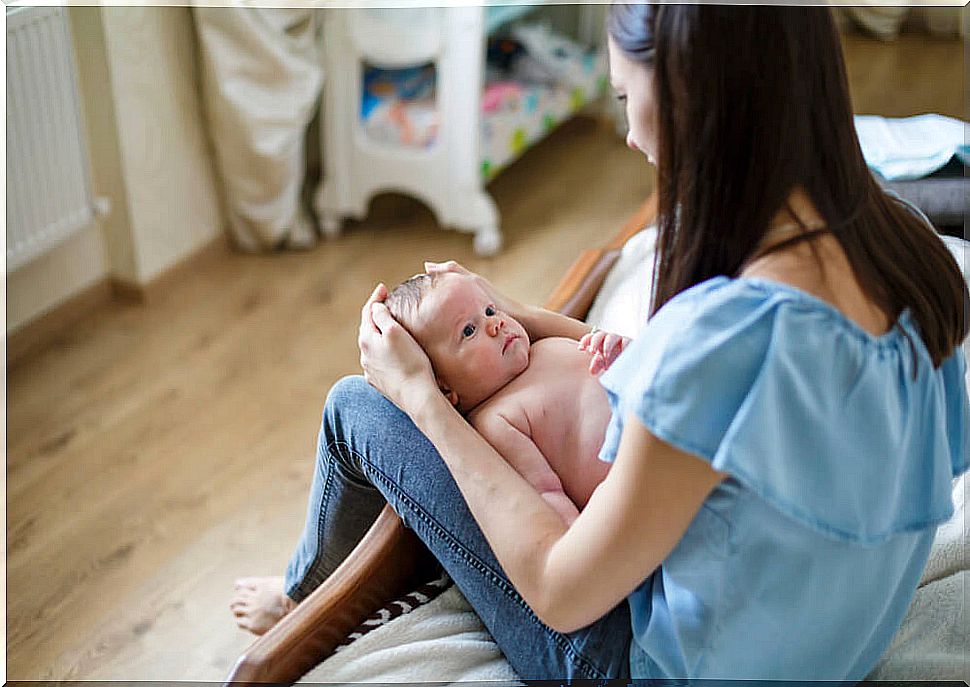 Mom with her baby propped up between her legs facing an identity crisis.