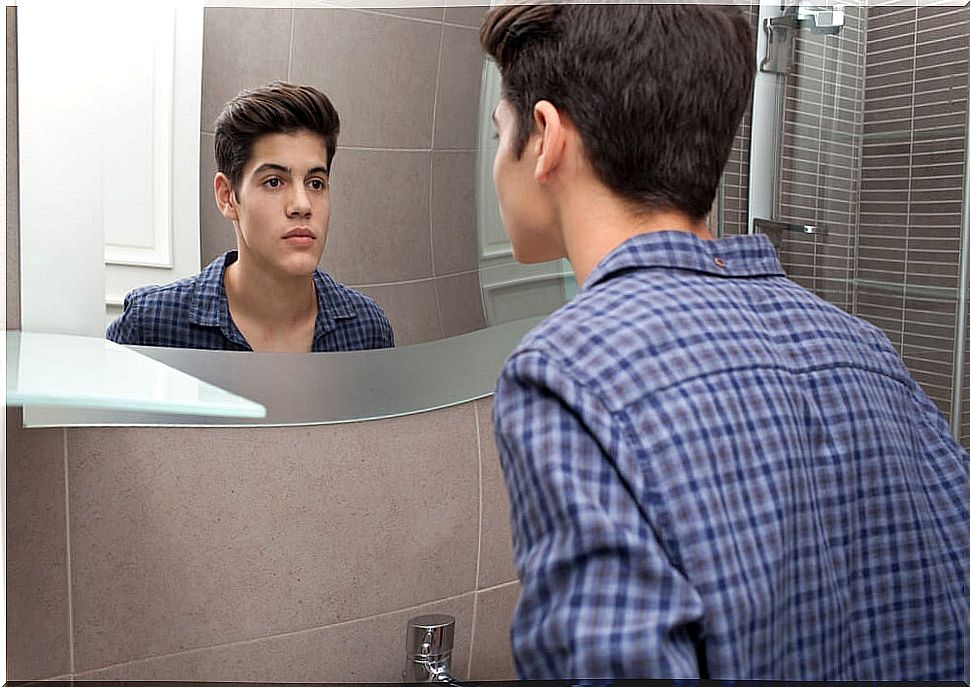 Teen boy looking in the mirror.